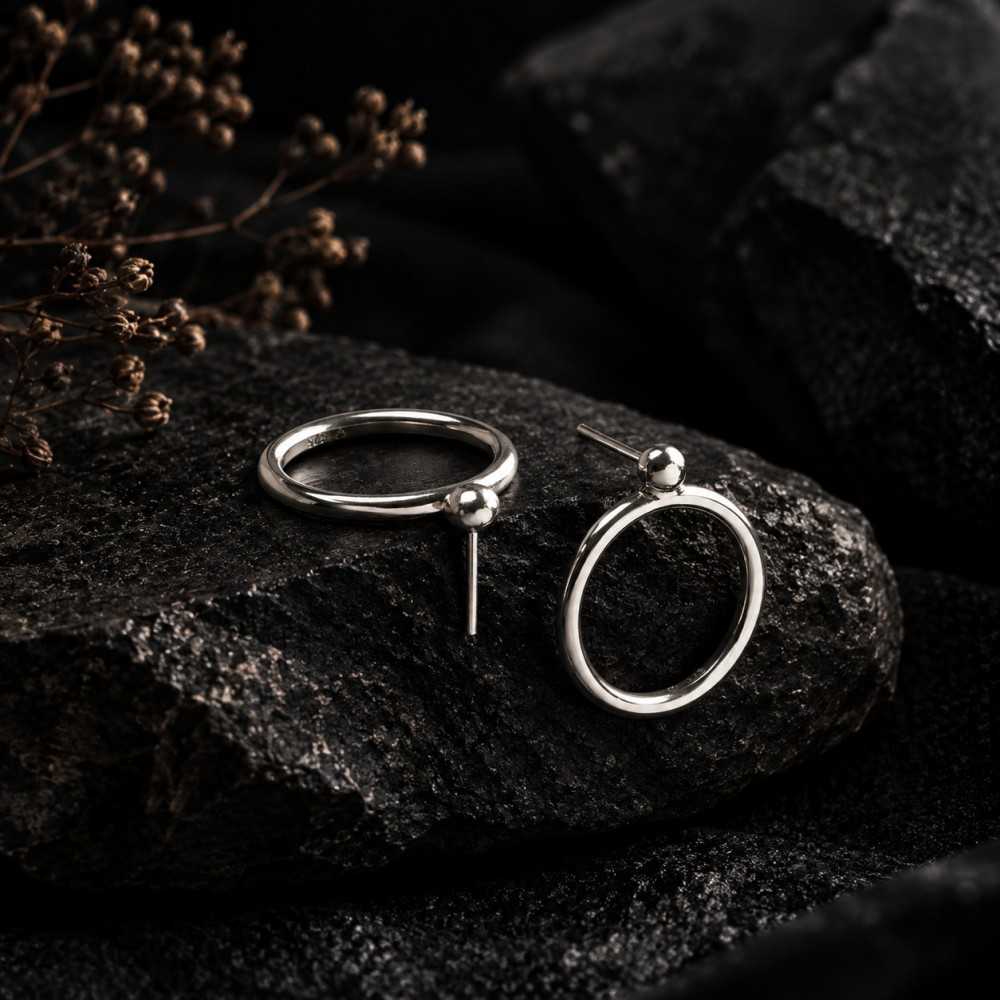 Puces d'oreilles rondes de style minimalistes en argent 925. Mise en scène générée par l'IA, le bijou est réel et fait main.
