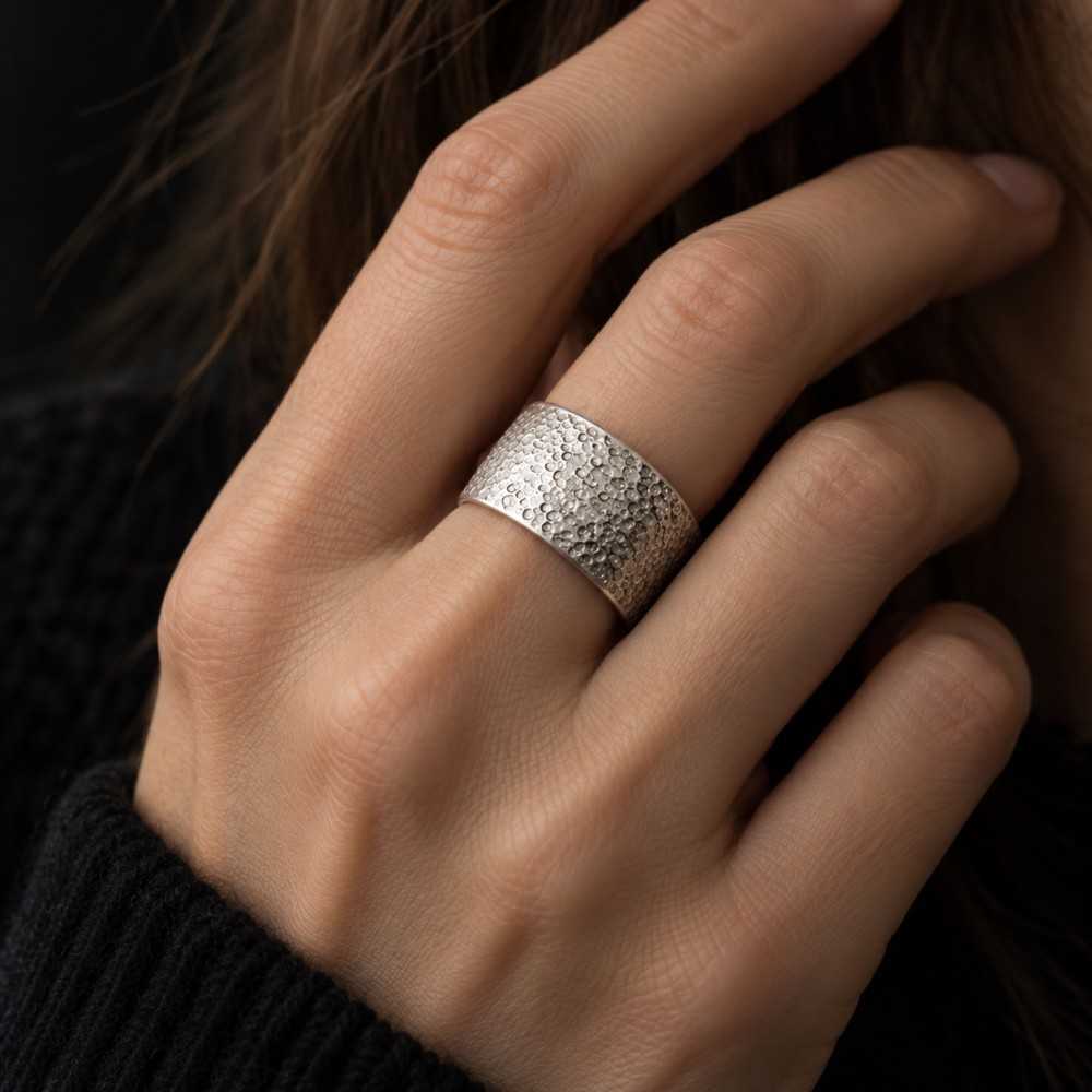 Bague large artisanale texturée portée en argent 925. Bague unisexe fait main en Suisse. Bague suisse à offrir.